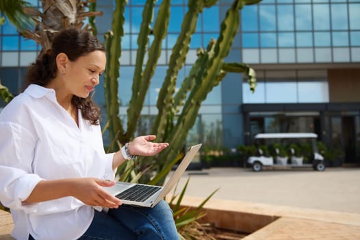 Side portrait of a female freelance entrepreneur using laptop, negotiating new startup project with investors or business partners via video link. People. Online communication. Career and recruitment