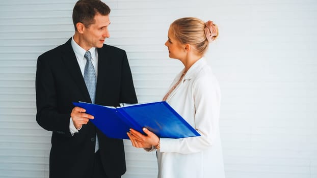 Two business people talk project strategy at office meeting room. Businessman discuss project planning with colleague at modern workplace while having conversation and advice on financial report. Jivy