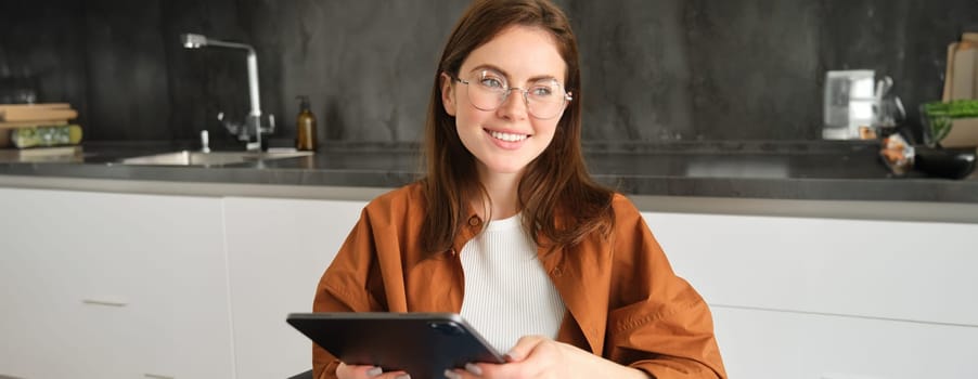 Portrait of beautiful young brunette woman, holding digital tablet, reading with glasses, smiling, surfing the net using gadget.