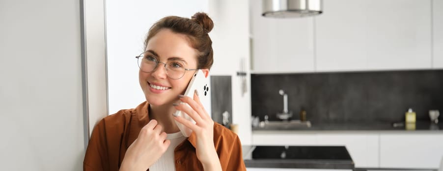 Portrait of happy smiling young woman at home, talking on mobile phone, calling friend and having nice conversation, answer telephone.