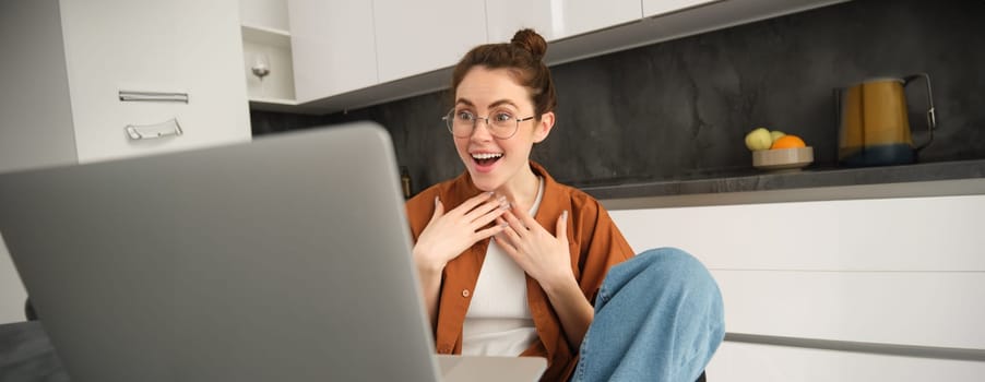 Work from home, remote job concept. Young woman sitting in kitchen, using laptop, joins video chat conversation, give online lessons, talking to client on computer.