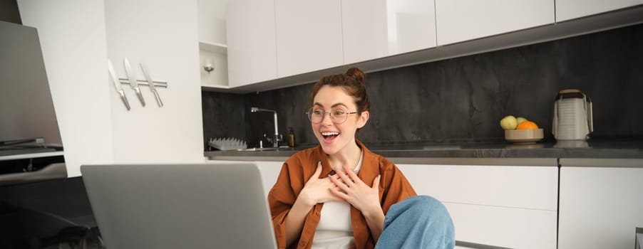 Portrait of young woman working from home, sitting at home with laptop, talking with friend on computer, online chatting, connects to video conversation.