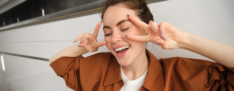 Carefree woman singing along song, listens to music in wireless headphones, enjoying sound quality, dancing with hands.