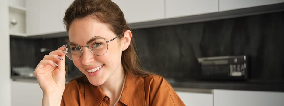 Close up portrait of beautiful brunette woman at home, smiling, wearing her glasses and laughing.