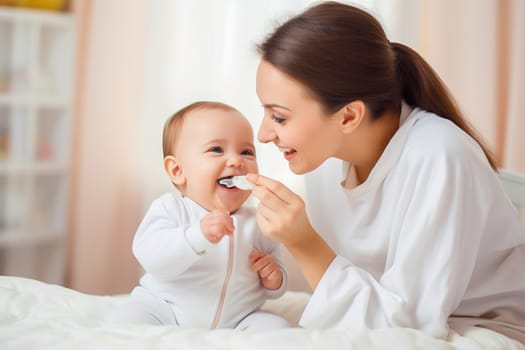 A happy mom feeds her baby from a spoon