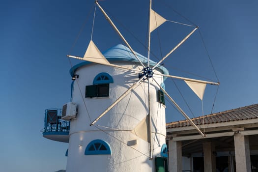 Beautiful view of the blue and white mill in the Greek style on a sunset summer evening, close-up side view.