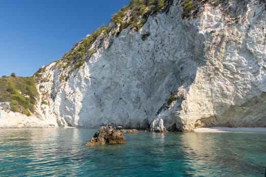 Beautiful view of a pebble beach in the rocks with clear water in the sea on a sunny summer day, close-up side view.