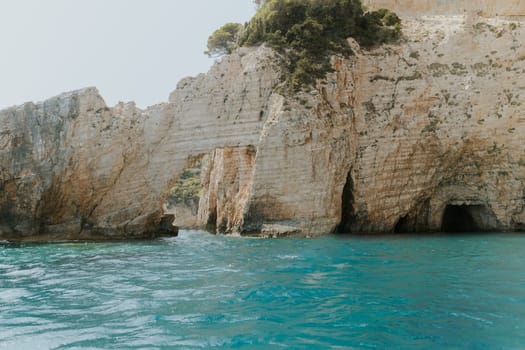 Beautiful view of a natural rocky arch in the blue sea on a sunny summer day, close-up side view.