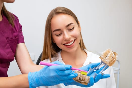 Dental hygienist demonstrate young woman how to clean teeth.