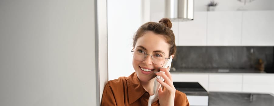 Portrait of happy woman at home, answers phone call, talking on mobile, holding smartphone and smiling.
