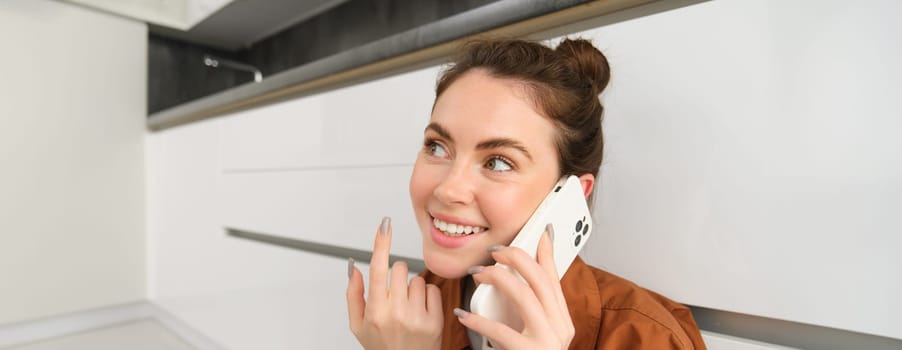 Close up of beautiful female model talks on phone, making a call, smiles and looks happy.