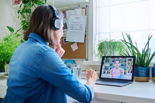 Young female teacher in headphones having video conference call with teenage girl student using laptop home. Online lesson e-learning distance remote classes technology in education knowledge school