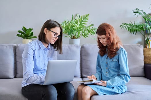 Individual lesson of teacher and child of preteen girl. Young woman teaching child, using laptop, student makes notes in notebook. Knowledge, education, teaching, tuition, school childhood concept