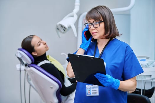 Dentist doctor nurse in the office talking on the phone. Dentistry, hygiene, treatment, medicine, dental health care concept