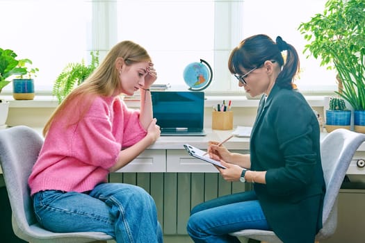 Female psychologist therapist working with young teen girl sitting in office. Teenage female student at therapy meeting with counselor. Psychology therapy psychotherapy youth mental health treatment