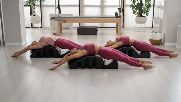 Balanced Body Pilates Arc. Three asian women exercising on pilates arc