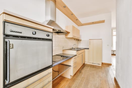 a kitchen with wood flooring and white walls, including an oven on the stove in the center of the room