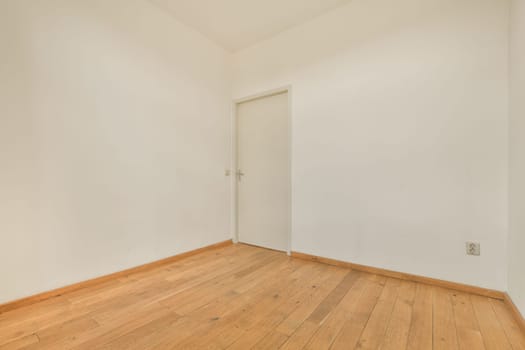 an empty room with white walls and wood flooring on the right, there is a door in the corner