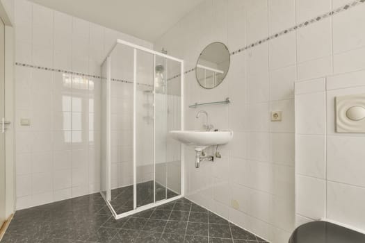 a bathroom with black and white tiles on the floor, shower stall and toilet in the room is very clean