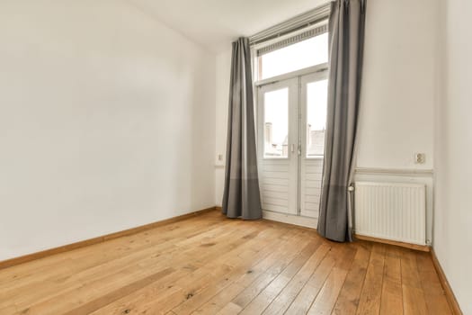 an empty room with wood flooring and white walls, showing the natural light coming in through the large window