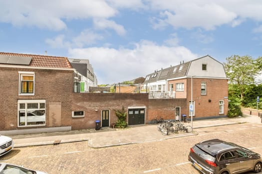 an empty street with cars parked on the side and two houses in the back, one building is red brick