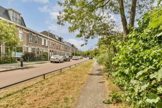 the street in front of an apartment building with trees and bushes on both sides, along one side of the road