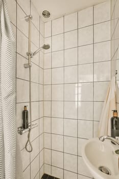 a bathroom with black and white tiles on the walls, shower headrests and hand held by a towel