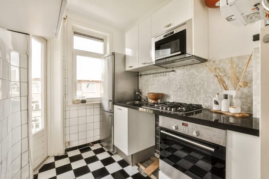 a kitchen with black and white tiles on the floor, including an oven, sink, microwave, toaster and dishwasher