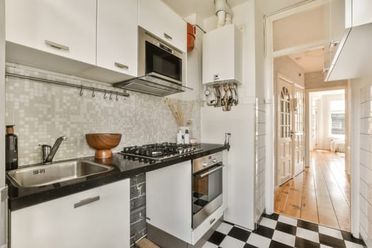 a small kitchen with black and white checkered tiles on the floor, along with an open door leading to another room