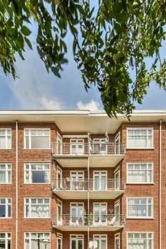 a brick apartment building with balks on the balcony and green trees in the fore - swayr stock photo