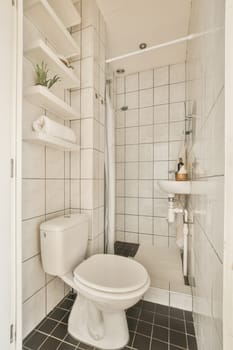 a small bathroom with black and white tiles on the floor, toilet, sink, and shower stall in it