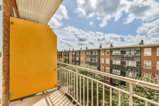 a balcony with some buildings in the background and blue sky above it, as seen from an apartment building's balcony