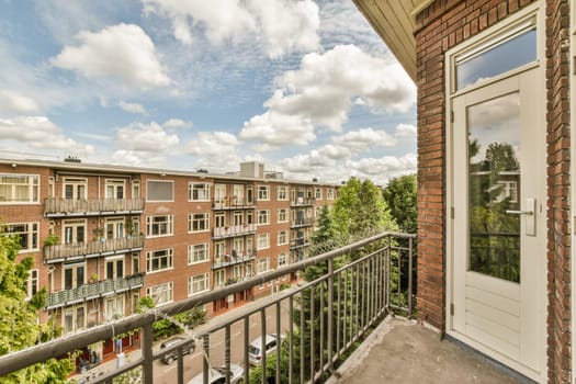 a balcony with some buildings in the background and trees on the other side of the building to the right, there is a white