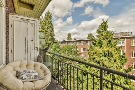 a balcony with a chair on it and some trees in the back yard behind, as seen from an apartment window