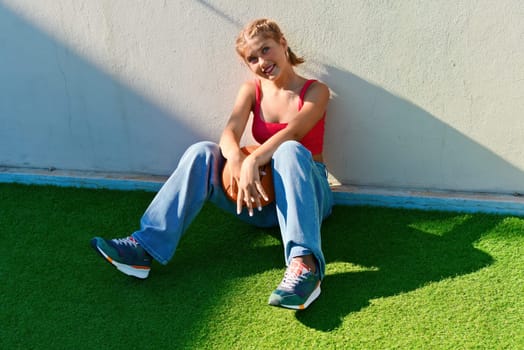 Cheerful teenage girl sitting on the sports ground.