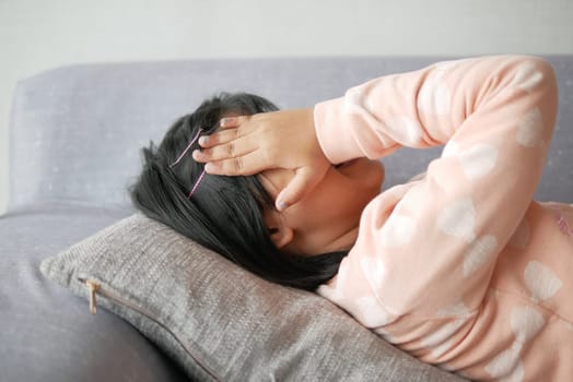 a upset child girl cover her face with hand .