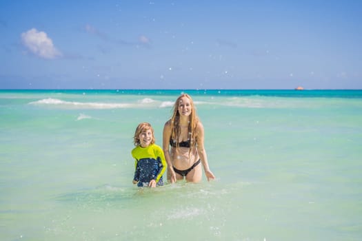 A radiant pregnant mother and her excited son share a tender moment on a serene, snow-white beach, celebrating family love amidst nature's beauty.