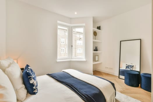 a bedroom with white walls and wood flooring the room has a large bed, two side tables and a mirror on the wall