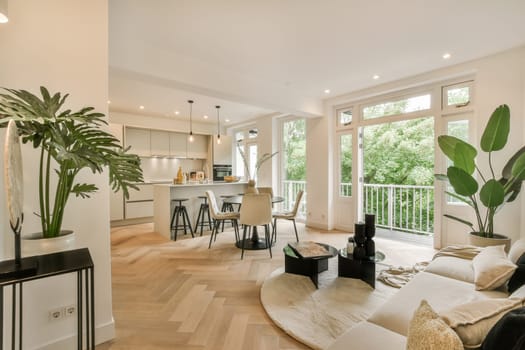 a living room with wood flooring and white walls that are open to the kitchen, dining area and balcony