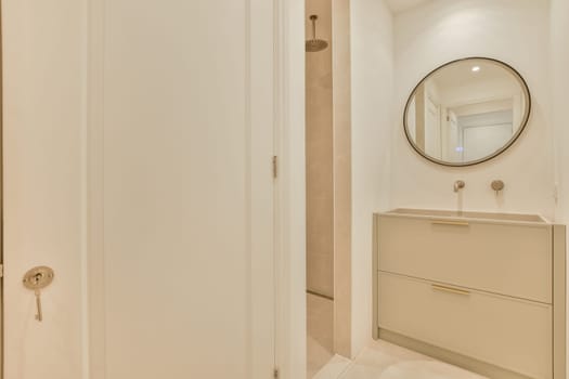 a bathroom with a mirror on the wall and white cupboards in front of the bathtub is next to the door