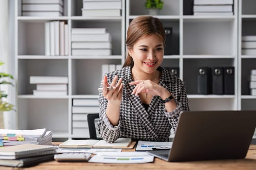 Attractive businesswoman uses calculator to do finance, mathematics on wooden table in office and business background, tax, accounting, statistics and analytical research concept..