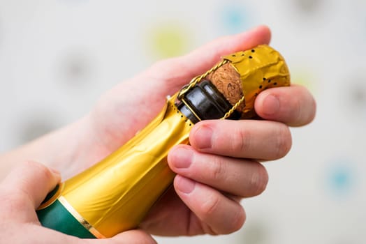 Mans hands are opening the bottle of champagne alcohol and wine drink on party celebration event. A man is opening the champagne bottle.