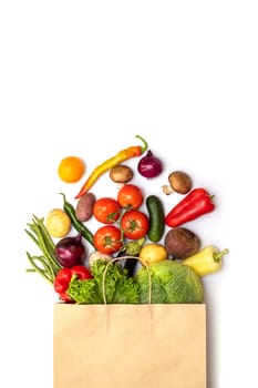 Fresh vegetables in eco friendly paper bag on white background, top view. Food delivery. Grocery shopping. Healthy eating concept.