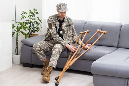 soldier in khaki military uniform on crutches.