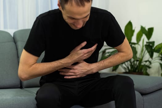 unhappy man suffering from stomach ache at home. High quality photo