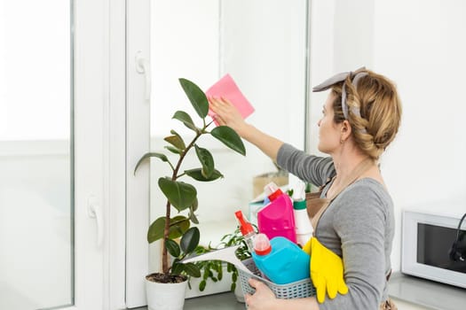 Woman cleaning and polishing the kitchen worktop with a spray detergent, housekeeping and hygiene concept