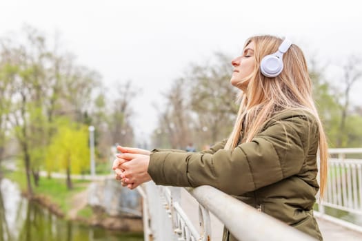 Relaxed woman wearing headphones breathing fresh air listening to music in a park.