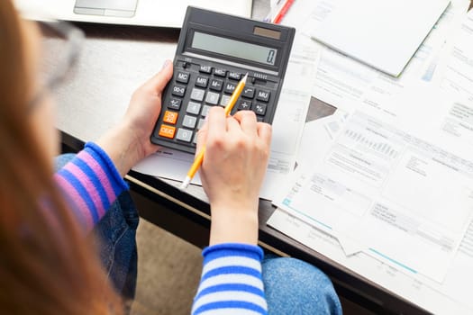 Woman using calculator for calculate domestic bills at home, doing paperwork for paying taxes