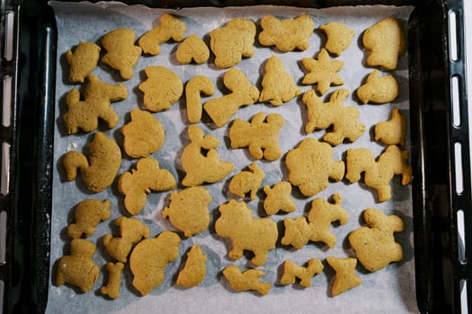 Freshly baked Christmas cookies lie on baking paper on a baking sheet. Top view. High quality photo