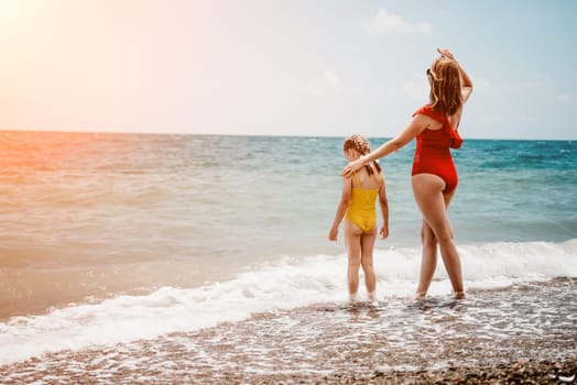 Happy loving family mother and daughter having fun together on the beach. Mum playing with her kid in holiday vacation next to the ocean - Family lifestyle and love concept.